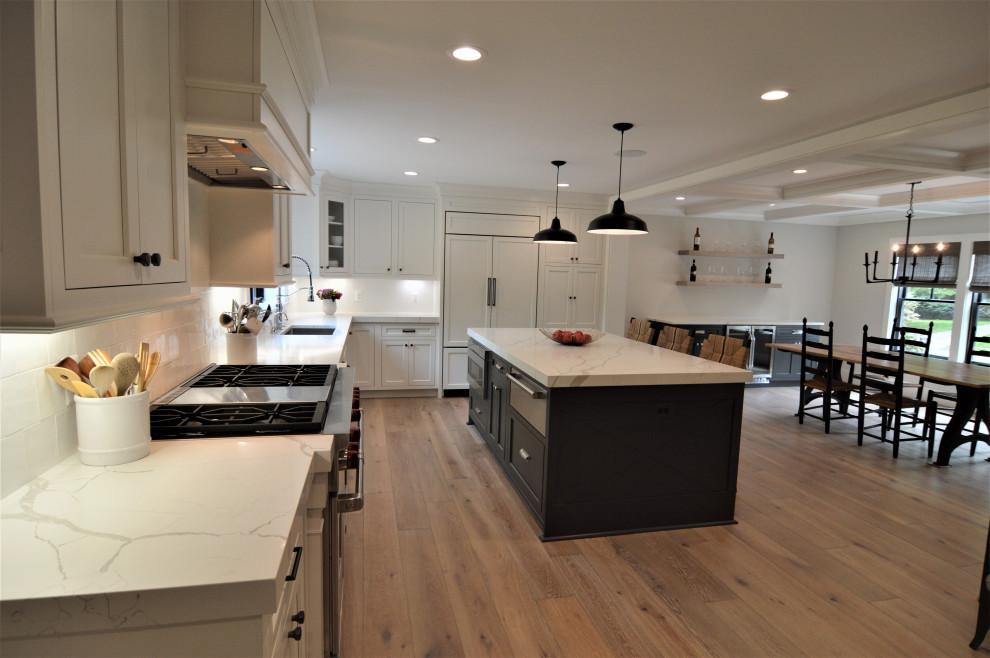 Eat-in kitchen - large transitional l-shaped light wood floor and brown floor eat-in kitchen idea in DC Metro with an undermount sink, recessed-panel cabinets, white cabinets, quartz countertops, white backsplash, ceramic backsplash, paneled appliances, an island and white countertops
