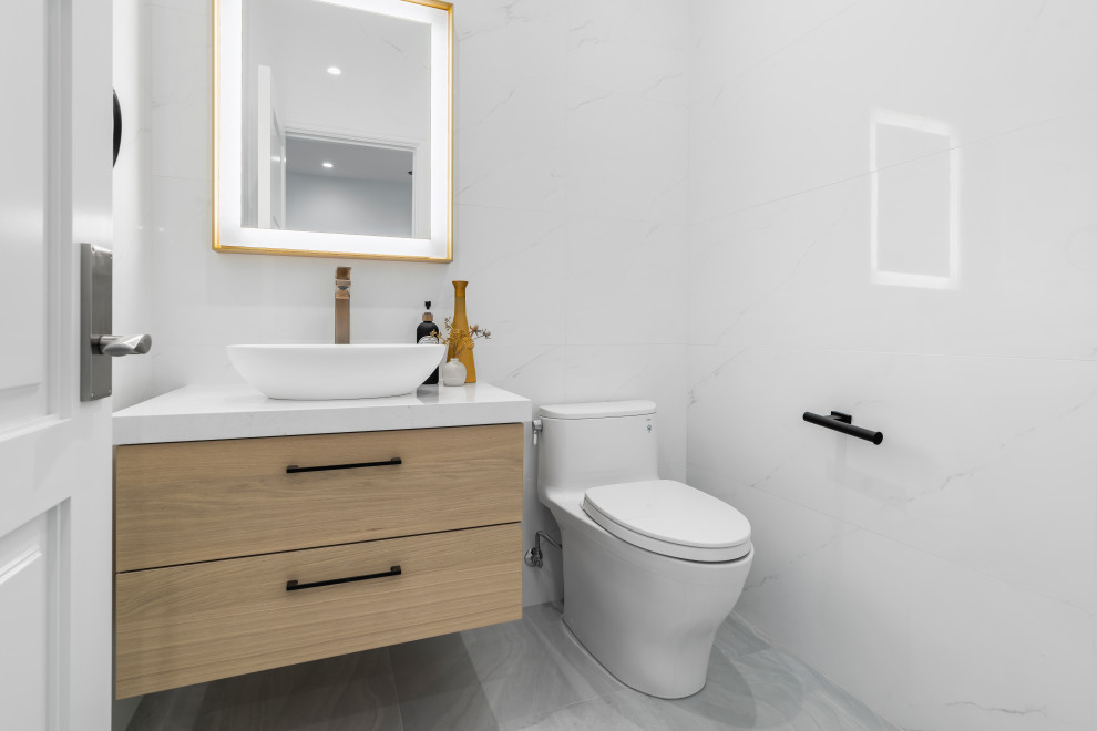 Idée de décoration pour une grande salle d'eau minimaliste en bois clair avec un placard en trompe-l'oeil, WC à poser, un carrelage blanc, des carreaux de porcelaine, un mur blanc, un sol en carrelage de porcelaine, un lavabo de ferme, un plan de toilette en quartz modifié, un sol gris, un plan de toilette blanc, meuble simple vasque et meuble-lavabo suspendu.
