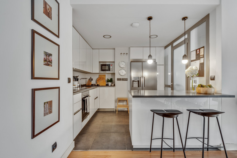 Eat-in kitchen - mid-sized scandinavian galley porcelain tile and gray floor eat-in kitchen idea in Madrid with a single-bowl sink, flat-panel cabinets, white cabinets, granite countertops, gray backsplash, metal backsplash, stainless steel appliances, an island and gray countertops