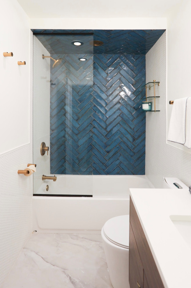 This is an example of a small transitional master bathroom in Chicago with flat-panel cabinets, brown cabinets, an alcove tub, a shower/bathtub combo, a one-piece toilet, blue tile, ceramic tile, white walls, porcelain floors, a drop-in sink, onyx benchtops, grey floor, a sliding shower screen, white benchtops, an enclosed toilet, a single vanity and a freestanding vanity.