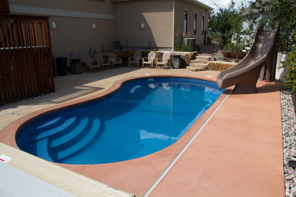 This is an example of a small backyard kidney-shaped pool in Denver with a water slide and concrete slab.