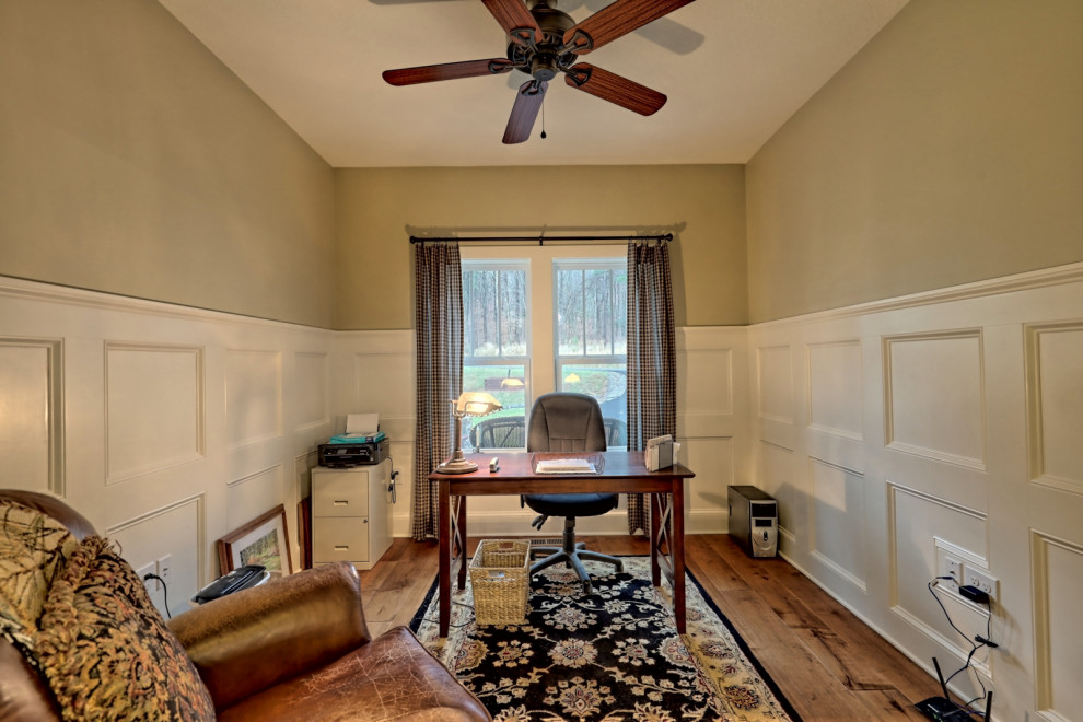 Mittelgroßes Rustikales Arbeitszimmer ohne Kamin mit grüner Wandfarbe, braunem Holzboden, freistehendem Schreibtisch, braunem Boden und vertäfelten Wänden in Atlanta