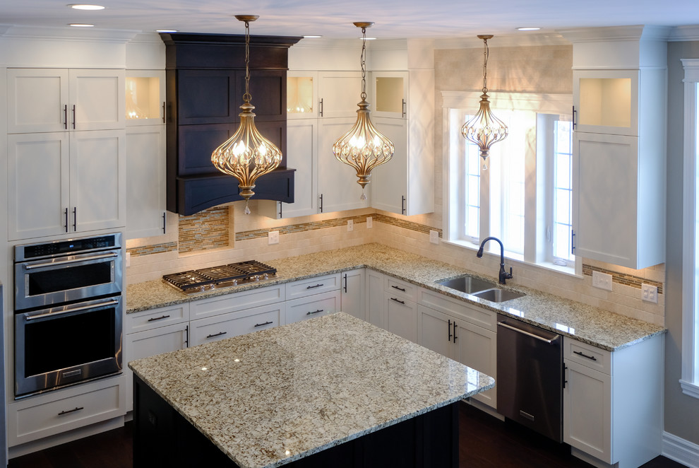 Inspiration for a large transitional u-shaped dark wood floor and brown floor eat-in kitchen remodel with an undermount sink, recessed-panel cabinets, white cabinets, granite countertops, beige backsplash, stainless steel appliances and an island