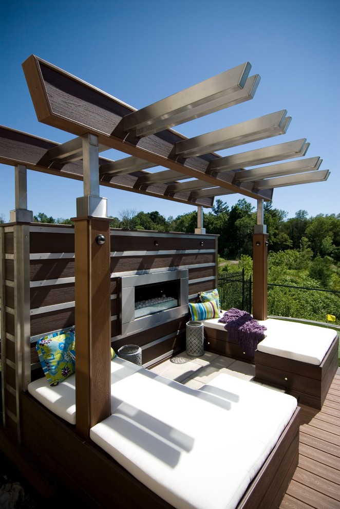 Large contemporary backyard deck in Toronto with a fire feature and a pergola.