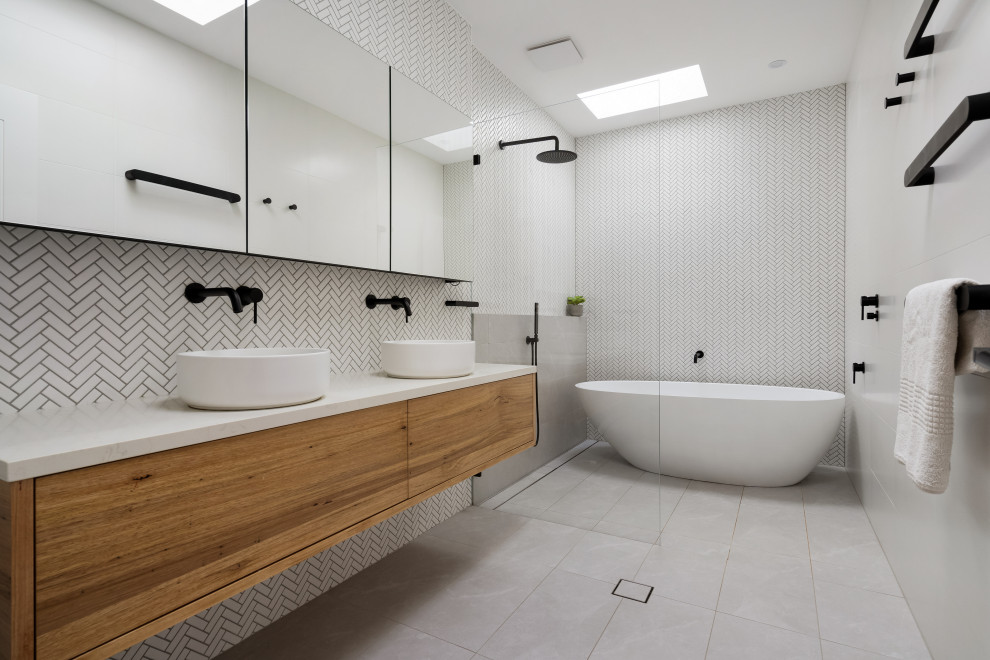 This is an example of a contemporary kids wet room bathroom in Sydney with light wood cabinets, a freestanding tub, white tile, porcelain tile, white walls, a vessel sink, engineered quartz benchtops, grey floor, an open shower, white benchtops, a niche, a double vanity and a floating vanity.