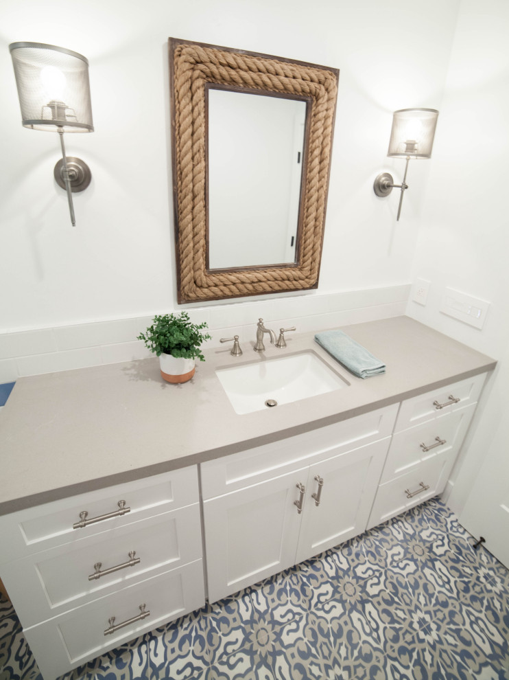 Design ideas for a mid-sized beach style kids bathroom in San Luis Obispo with shaker cabinets, white cabinets, an alcove tub, a shower/bathtub combo, a one-piece toilet, white tile, porcelain tile, white walls, cement tiles, an undermount sink, engineered quartz benchtops, grey floor, a shower curtain and grey benchtops.