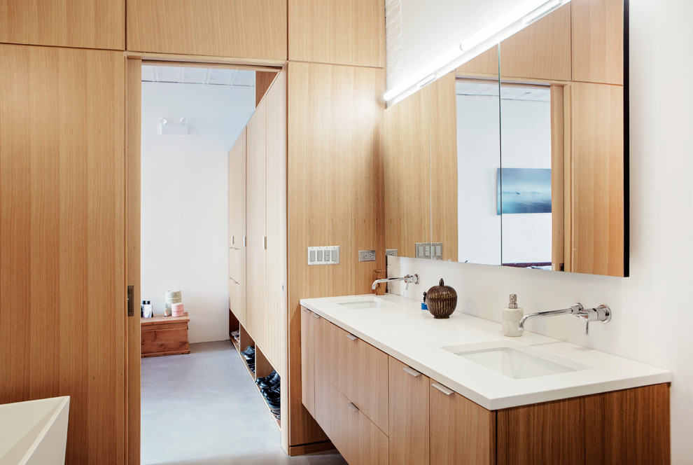 This is an example of a large modern master bathroom in Chicago with flat-panel cabinets, light wood cabinets, a freestanding tub, a double shower, a wall-mount toilet, beige walls, concrete floors, an undermount sink, engineered quartz benchtops, grey floor, a hinged shower door and white benchtops.