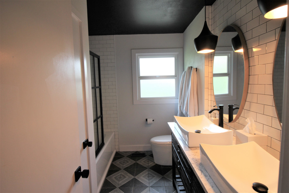 Small transitional kids bathroom in Portland with black cabinets, an alcove tub, a shower/bathtub combo, a one-piece toilet, white tile, subway tile, white walls, ceramic floors, a vessel sink, engineered quartz benchtops, black floor, multi-coloured benchtops, a double vanity and a freestanding vanity.