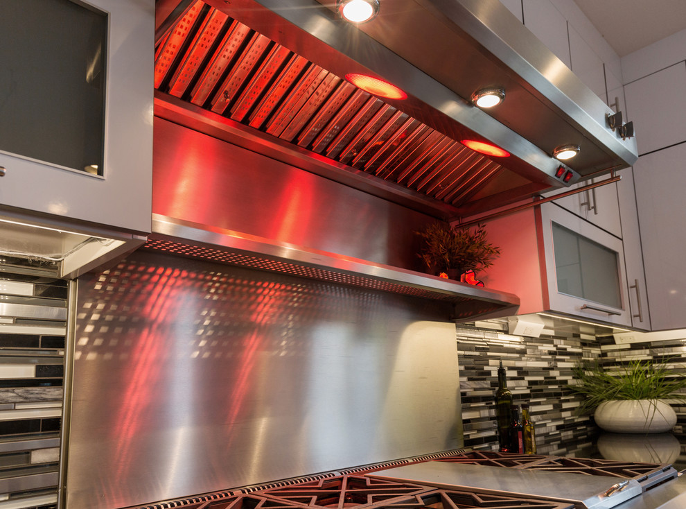 Open concept kitchen - large contemporary u-shaped light wood floor open concept kitchen idea with an undermount sink, flat-panel cabinets, white cabinets, granite countertops, multicolored backsplash, mosaic tile backsplash, stainless steel appliances and an island