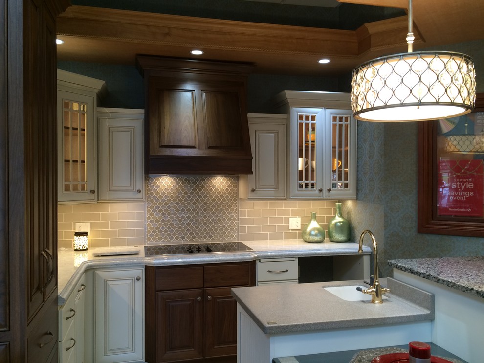 This is an example of a mid-sized transitional u-shaped eat-in kitchen in Milwaukee with raised-panel cabinets, white cabinets, with island, an undermount sink, quartzite benchtops, grey splashback, mosaic tile splashback, stainless steel appliances and light hardwood floors.