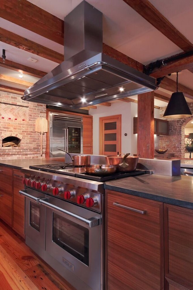 Inspiration for a large industrial l-shaped eat-in kitchen in Boston with an undermount sink, flat-panel cabinets, medium wood cabinets, granite benchtops, grey splashback, brick splashback, stainless steel appliances, medium hardwood floors, multiple islands and brown floor.