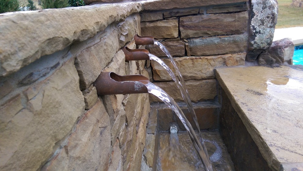 Inspiration for a rustic backyard stone and kidney-shaped lap pool fountain remodel