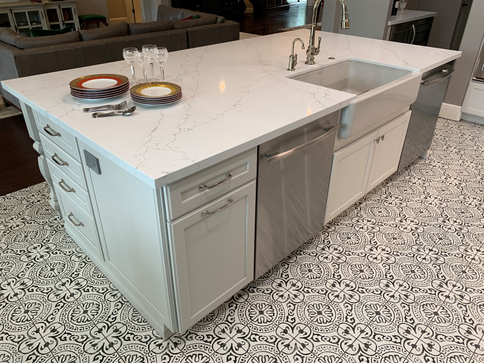 Example of a transitional l-shaped porcelain tile and multicolored floor kitchen design in Houston with a farmhouse sink, recessed-panel cabinets, white cabinets, quartz countertops, gray backsplash, ceramic backsplash, stainless steel appliances, an island and white countertops