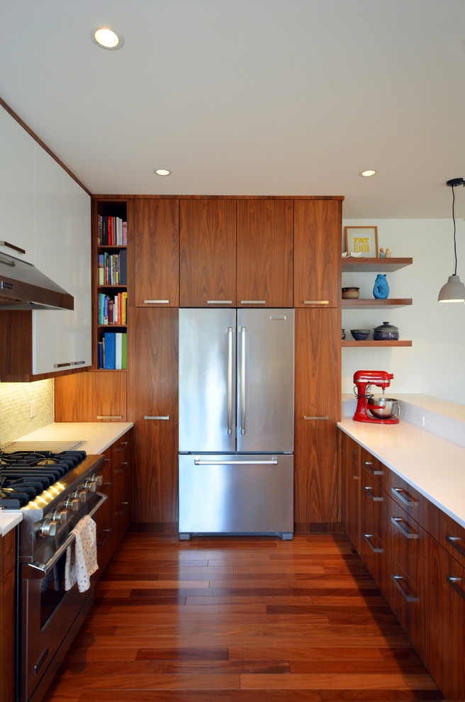 Photo of a contemporary u-shaped eat-in kitchen in Calgary with an undermount sink, flat-panel cabinets, medium wood cabinets, quartz benchtops, white splashback and stainless steel appliances.