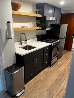 Enclosed kitchen - small transitional single-wall light wood floor and brown floor enclosed kitchen idea in Boston with an undermount sink, shaker cabinets, blue cabinets, quartz countertops, stainless steel appliances, no island and white countertops