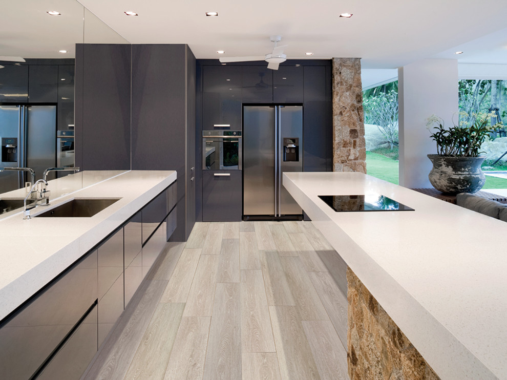 Design ideas for a large modern l-shaped open plan kitchen in Orange County with a single-bowl sink, flat-panel cabinets, grey cabinets, quartz benchtops, mirror splashback, stainless steel appliances, light hardwood floors, with island, brown floor and grey benchtop.