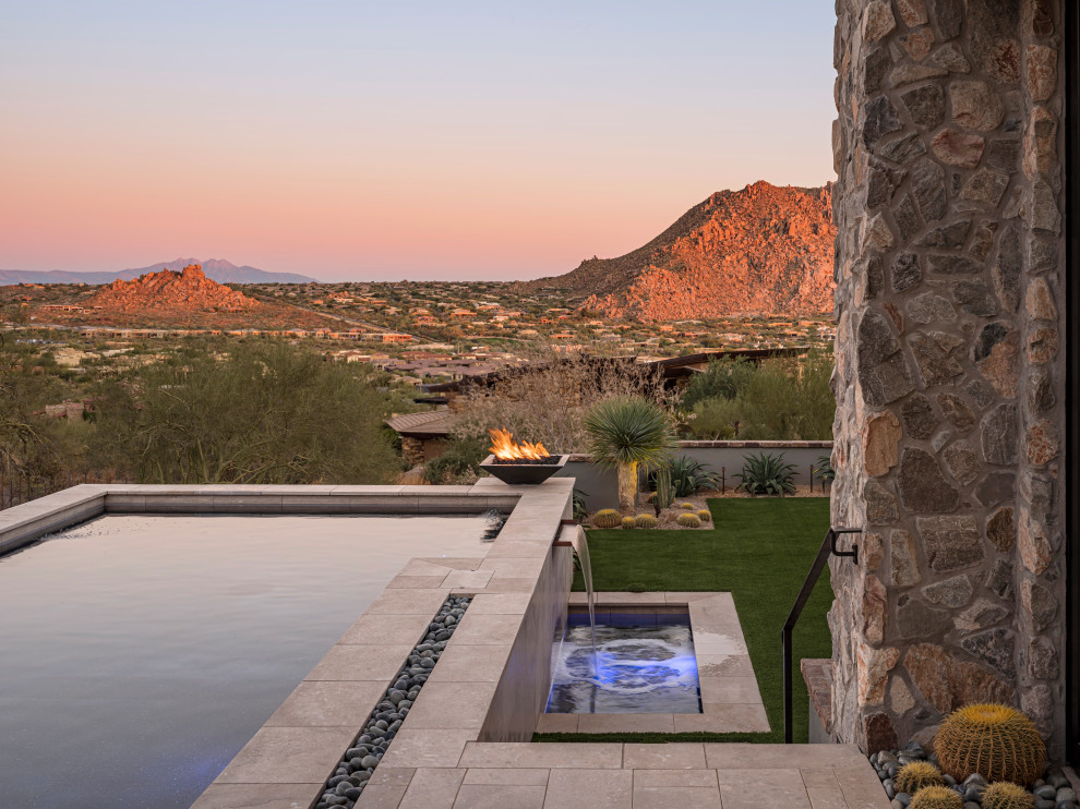 Large southwestern gray two-story stone house exterior idea in Phoenix with a hip roof, a tile roof and a black roof