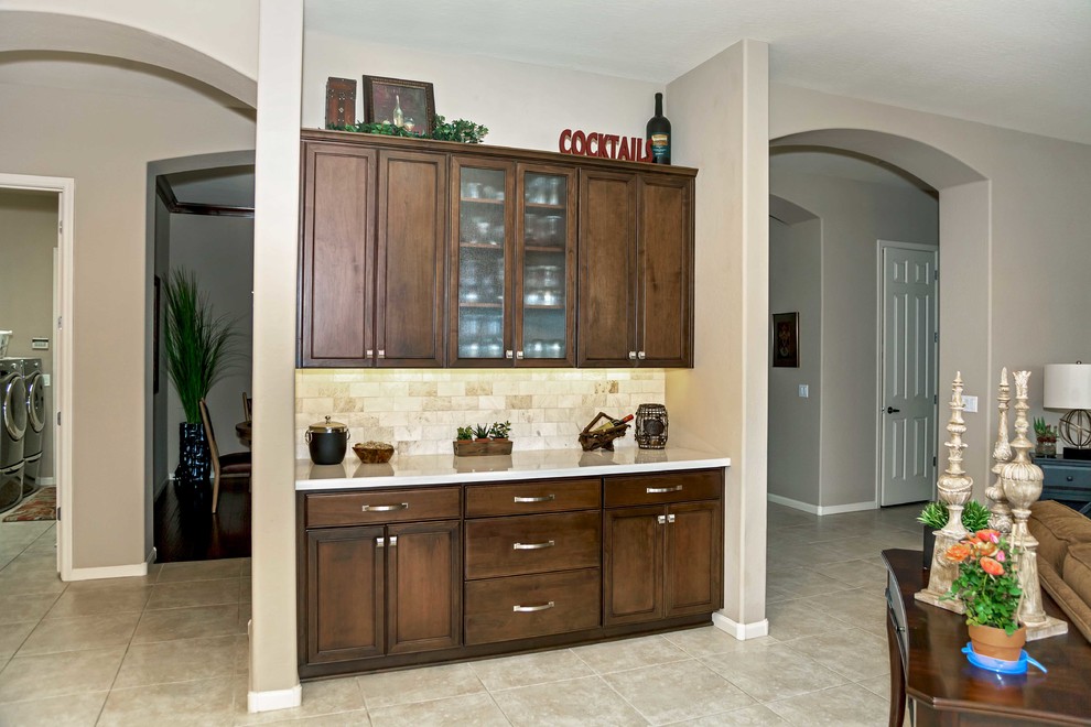 Transitional ceramic tile eat-in kitchen photo in Phoenix with an undermount sink, recessed-panel cabinets, dark wood cabinets, quartzite countertops, gray backsplash, stone tile backsplash, stainless steel appliances and an island