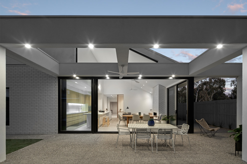 Inspiration for a mid-sized beach style backyard patio in Sydney with concrete pavers and a pergola.