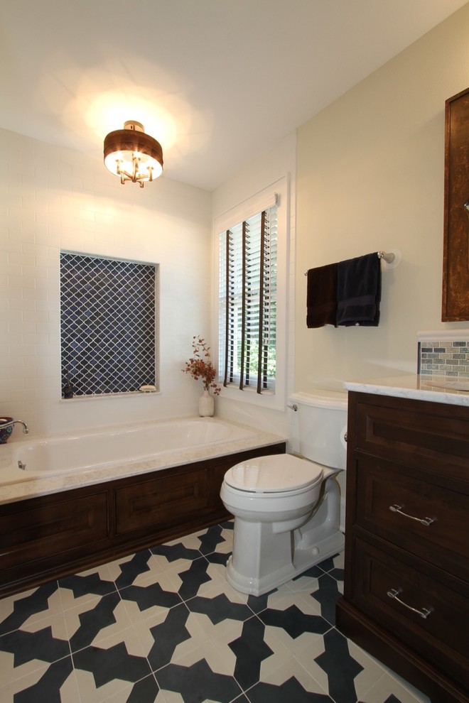 Large mediterranean master bathroom in Milwaukee with furniture-like cabinets, dark wood cabinets, a drop-in tub, a two-piece toilet, white tile, subway tile, beige walls, cement tiles, an undermount sink, engineered quartz benchtops, a hinged shower door, an alcove shower and blue floor.