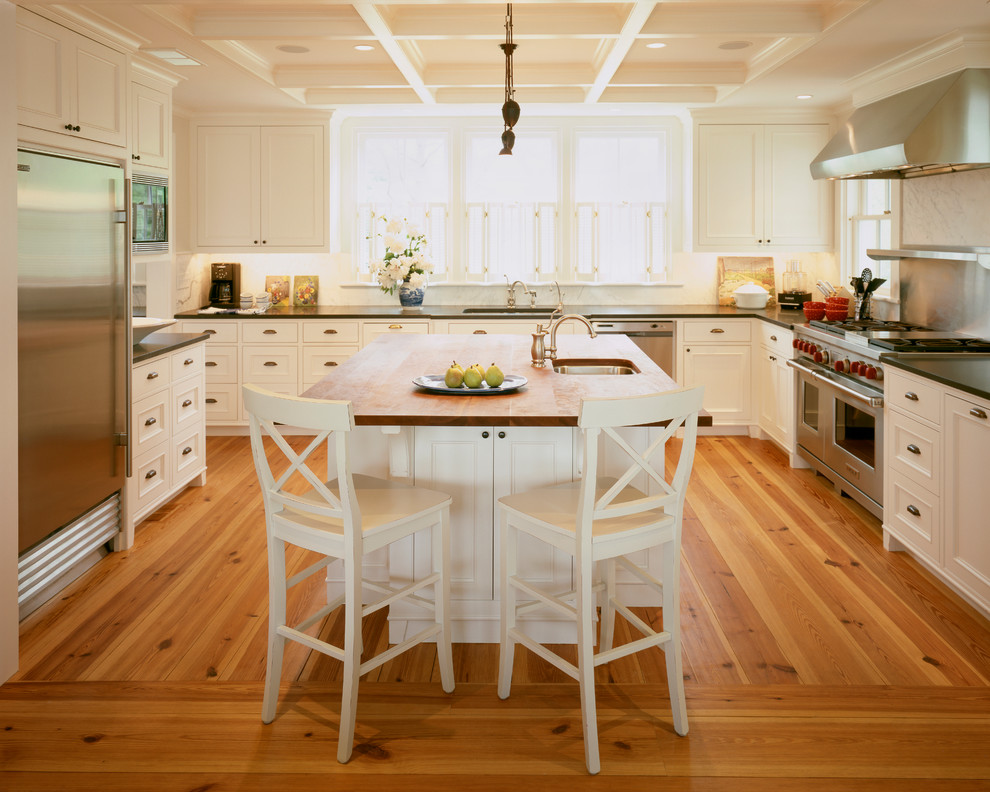 Photo of a traditional u-shaped kitchen in Boston with wood benchtops, recessed-panel cabinets, white cabinets, stone slab splashback and stainless steel appliances.