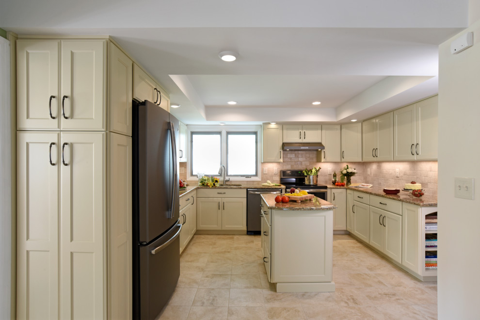 Example of a mid-sized transitional u-shaped porcelain tile, beige floor and tray ceiling enclosed kitchen design with an undermount sink, flat-panel cabinets, beige cabinets, quartz countertops, beige backsplash, travertine backsplash, black appliances, an island and beige countertops