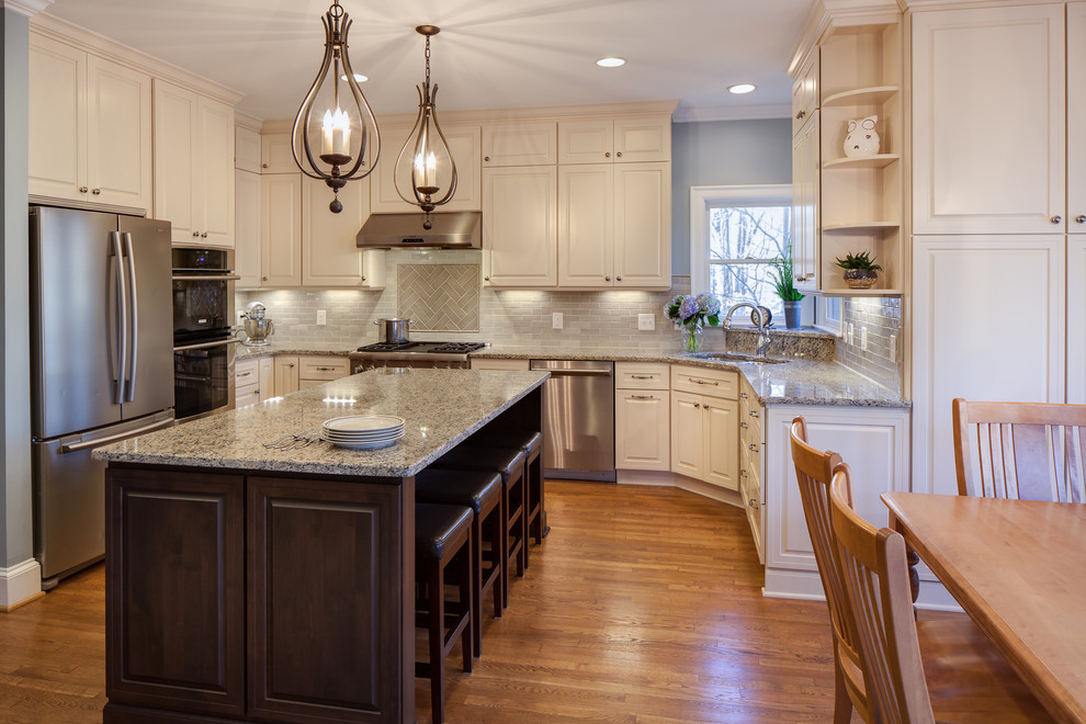This is an example of a mid-sized traditional u-shaped eat-in kitchen in Charlotte with an undermount sink, raised-panel cabinets, white cabinets, blue splashback, ceramic splashback, stainless steel appliances, medium hardwood floors, granite benchtops and with island.