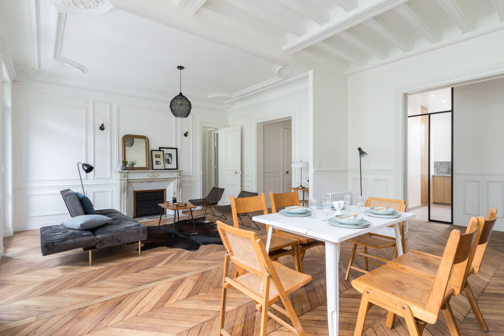 Photo of a large contemporary dining room in Paris with white walls, medium hardwood floors, a standard fireplace, a stone fireplace surround, brown floor, exposed beam and decorative wall panelling.