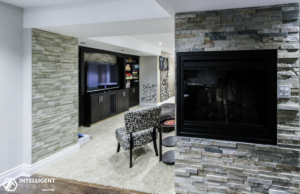 Large transitional underground vinyl floor, multicolored floor and brick wall basement photo in Toronto with gray walls and a wood stove