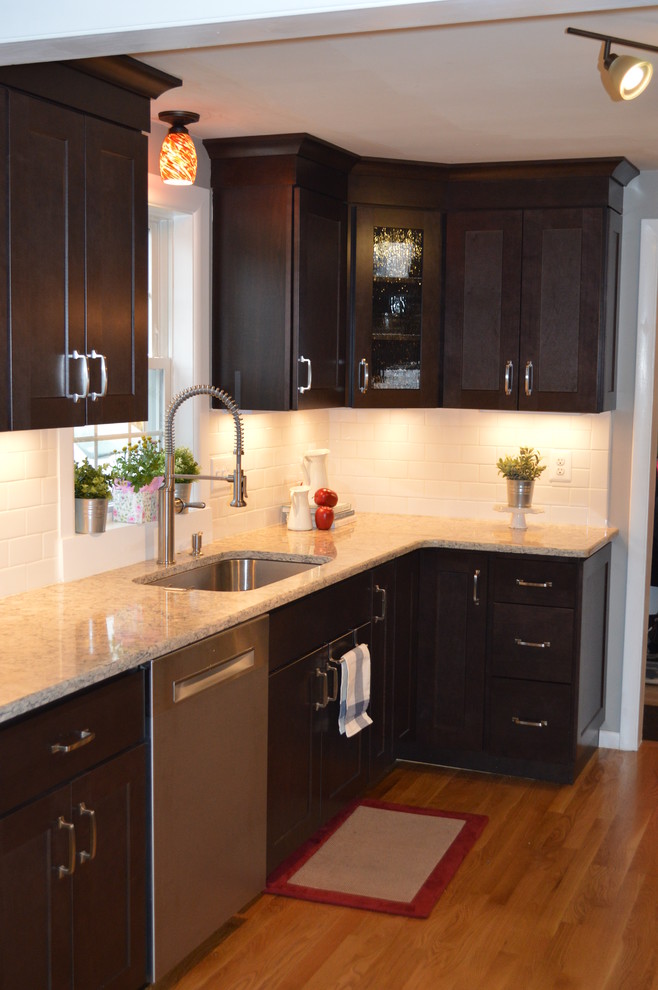 Kitchen - transitional galley light wood floor kitchen idea in Boston with an undermount sink, shaker cabinets, dark wood cabinets, quartz countertops, white backsplash, ceramic backsplash and stainless steel appliances