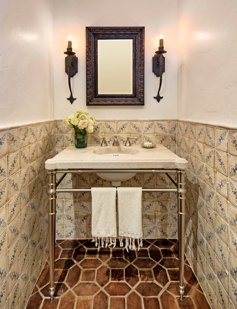 Small mediterranean powder room in Santa Barbara with a console sink, beige tile, brown tile, ceramic tile, white walls, terra-cotta floors and beige benchtops.