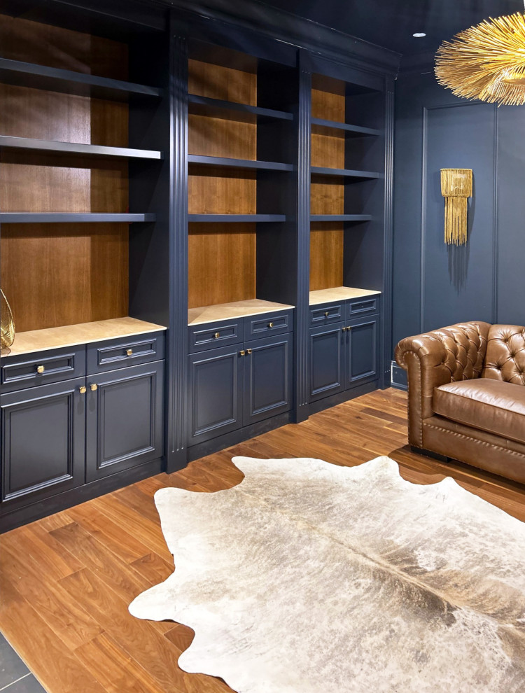 Immagine di uno studio classico di medie dimensioni con libreria, pareti blu, pavimento in legno massello medio e pannellatura