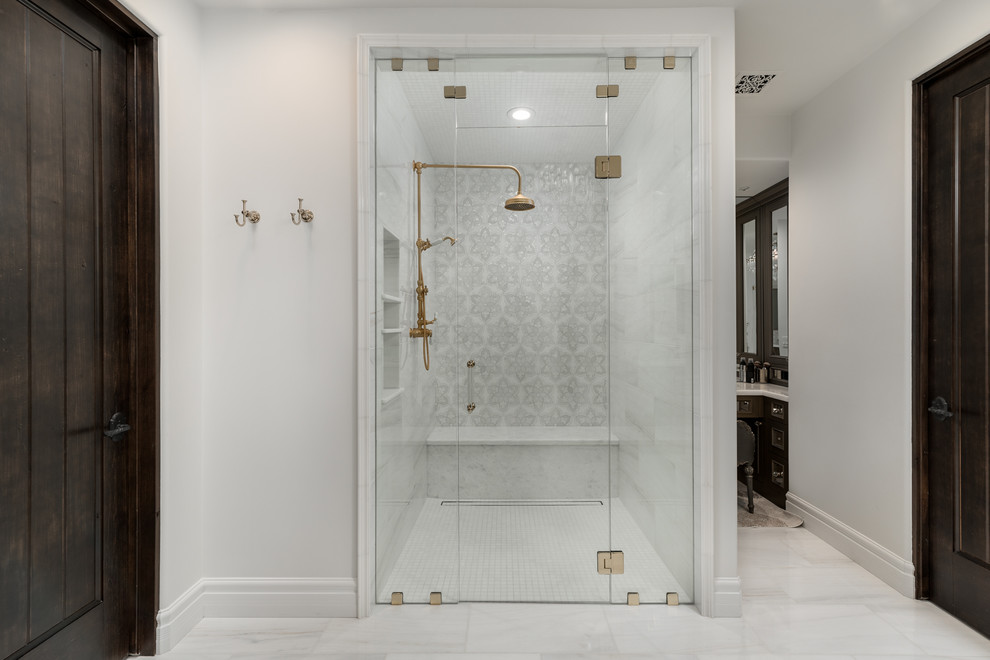Design ideas for an expansive mediterranean master bathroom in Phoenix with recessed-panel cabinets, black cabinets, white floor, a freestanding tub, an alcove shower, a one-piece toilet, multi-coloured tile, porcelain tile, white walls, marble floors, a wall-mount sink, marble benchtops, a hinged shower door and white benchtops.