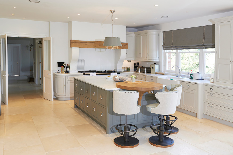 Photo of a large country l-shaped open plan kitchen in Hampshire with a farmhouse sink, shaker cabinets, grey cabinets, marble benchtops, limestone floors, a peninsula and beige floor.