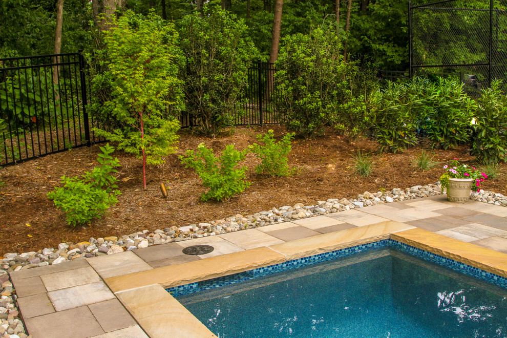 Large arts and crafts side yard rectangular lap pool in Other with a pool house and natural stone pavers.
