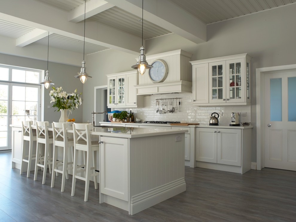 Design ideas for a large traditional open plan kitchen in Dublin with an integrated sink, recessed-panel cabinets, white cabinets, white splashback, subway tile splashback, stainless steel appliances and with island.