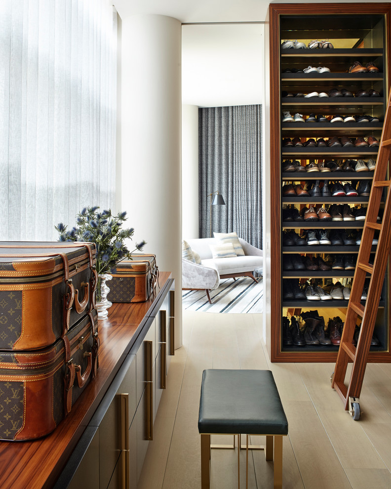 This is an example of a traditional men's storage and wardrobe in New York with open cabinets, dark wood cabinets and light hardwood floors.