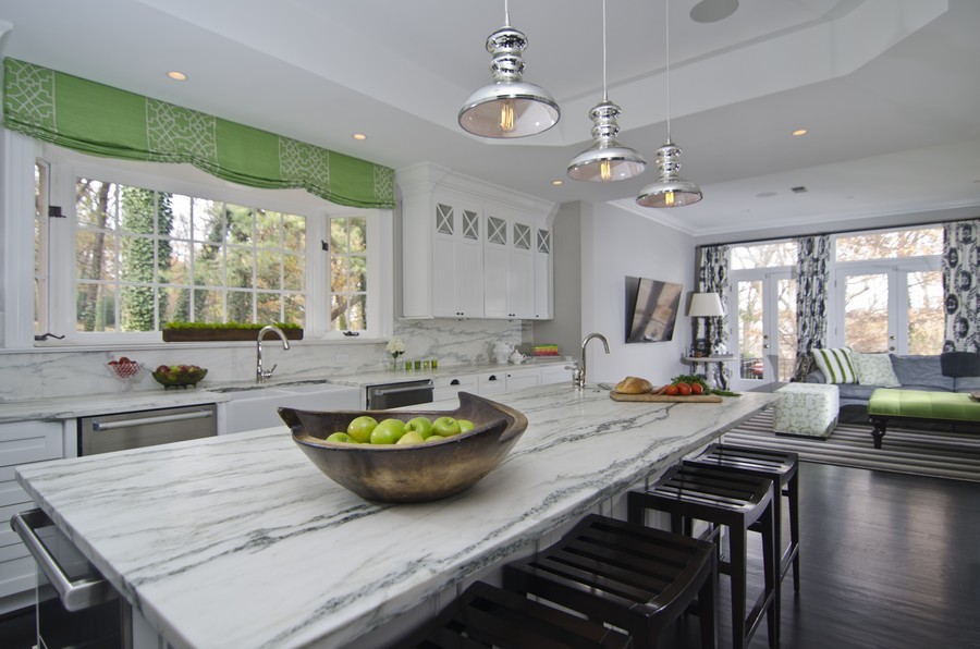 Inspiration for a transitional dark wood floor kitchen remodel with a farmhouse sink, shaker cabinets, white cabinets, marble countertops, gray backsplash, stainless steel appliances and an island