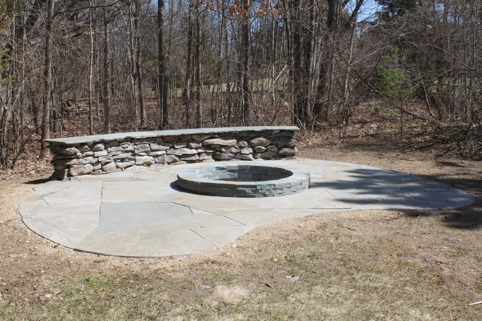 Mid-sized country backyard patio in Detroit with a fire feature, natural stone pavers and no cover.