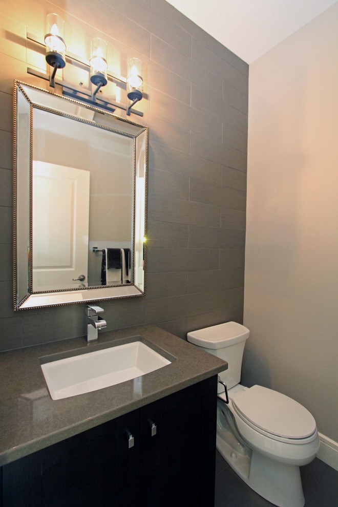Photo of a small contemporary 3/4 bathroom in Other with shaker cabinets, dark wood cabinets, a two-piece toilet, gray tile, porcelain tile, beige walls, porcelain floors, an undermount sink and quartzite benchtops.