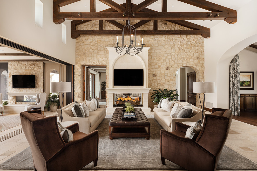 Design ideas for a mediterranean open concept family room in Phoenix with beige walls, a two-sided fireplace, a stone fireplace surround and a wall-mounted tv.