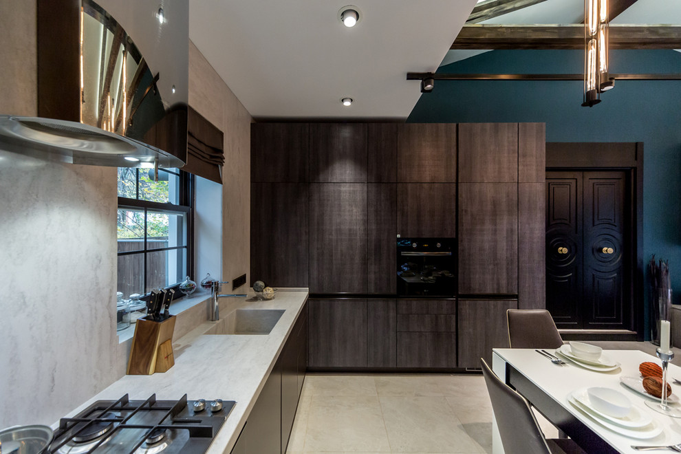 This is an example of a large industrial l-shaped eat-in kitchen in Novosibirsk with flat-panel cabinets, dark wood cabinets, solid surface benchtops, black appliances, ceramic floors, no island, beige floor and white benchtop.