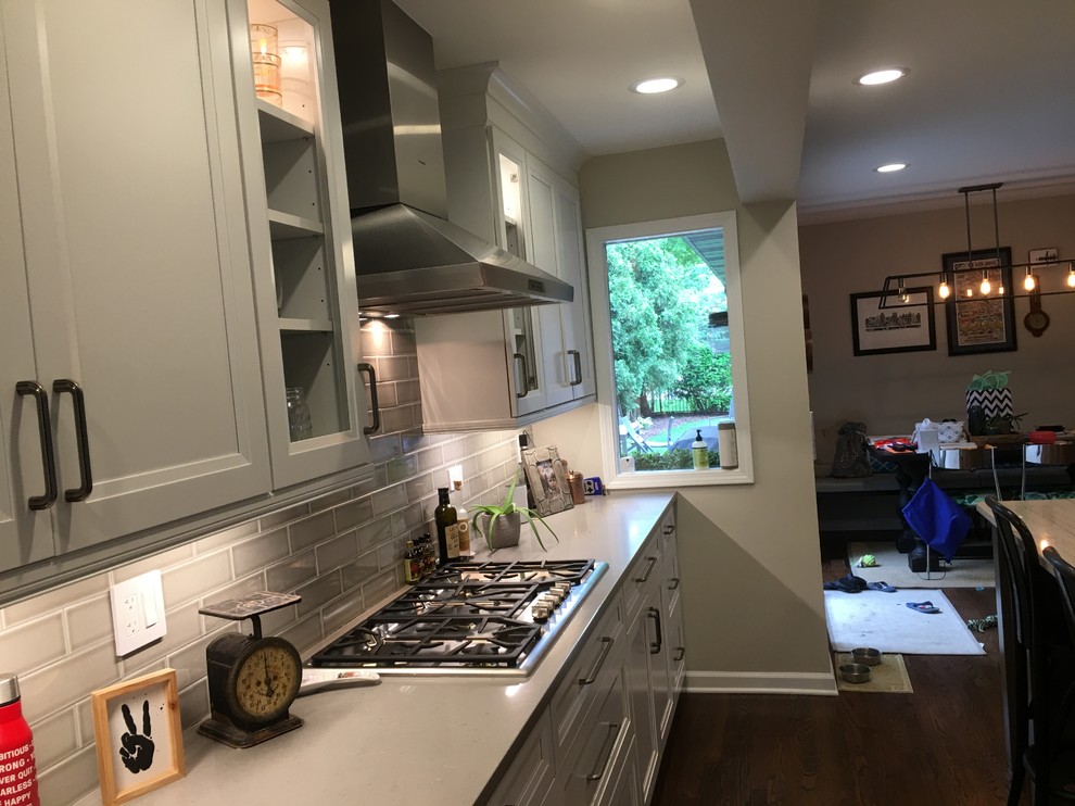 Open concept kitchen - large transitional u-shaped dark wood floor and brown floor open concept kitchen idea in Chicago with an undermount sink, flat-panel cabinets, white cabinets, quartz countertops, gray backsplash, ceramic backsplash, stainless steel appliances, an island and gray countertops