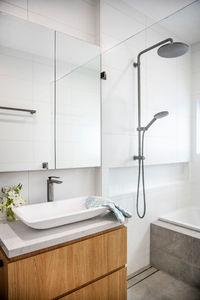 Inspiration for a mid-sized beach style master bathroom in Sydney with light wood cabinets, a drop-in tub, an open shower, a one-piece toilet, white tile, ceramic tile, white walls, ceramic floors, a vessel sink, engineered quartz benchtops, grey floor, an open shower, white benchtops and flat-panel cabinets.
