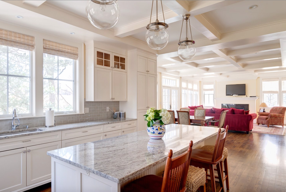 Design ideas for a large transitional u-shaped open plan kitchen in Boston with a drop-in sink, recessed-panel cabinets, white cabinets, quartz benchtops, glass tile splashback, stainless steel appliances, medium hardwood floors and with island.