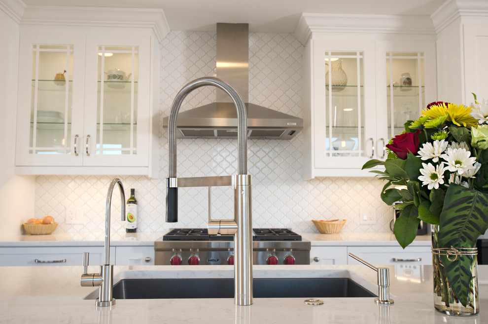 Inspiration for a transitional galley limestone floor eat-in kitchen remodel with an undermount sink, white cabinets, quartz countertops, white backsplash, ceramic backsplash, stainless steel appliances and an island
