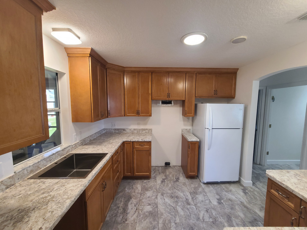 Eat-in kitchen - mid-sized l-shaped eat-in kitchen idea with flat-panel cabinets, medium tone wood cabinets, laminate countertops, an island and white countertops