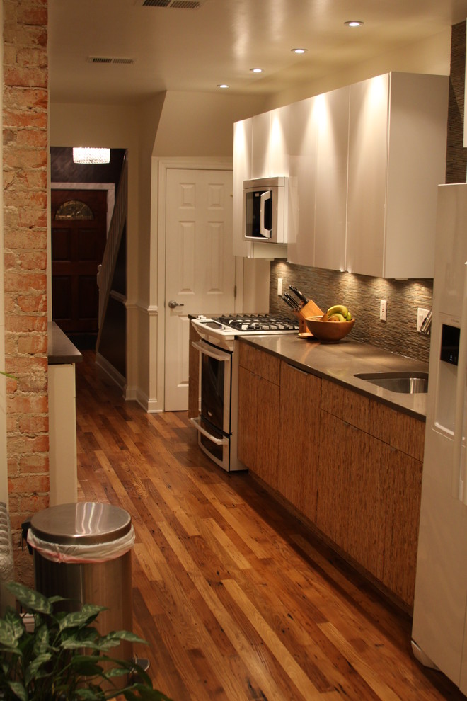 Photo of a small traditional galley kitchen in DC Metro with a single-bowl sink, flat-panel cabinets, dark wood cabinets, solid surface benchtops, brown splashback, stone tile splashback, white appliances, dark hardwood floors and brown floor.
