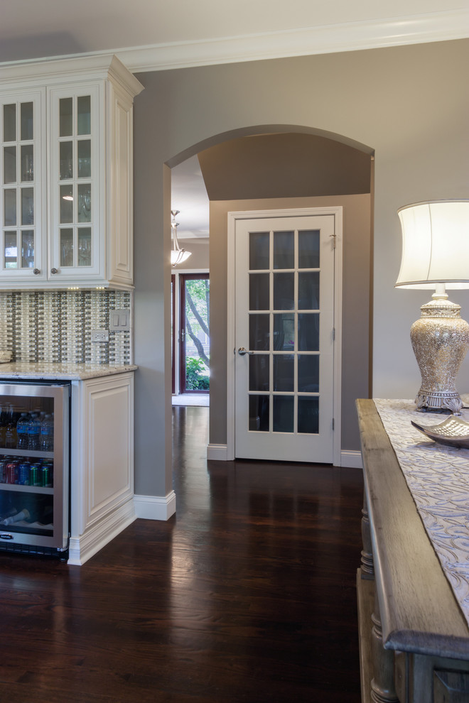 Example of a large transitional u-shaped dark wood floor kitchen design in Chicago with a double-bowl sink, raised-panel cabinets, white cabinets, granite countertops, gray backsplash, subway tile backsplash, stainless steel appliances and an island