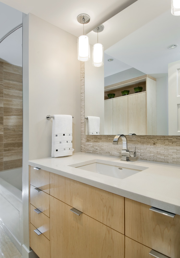 Mid-sized contemporary kids bathroom in Ottawa with an undermount sink, flat-panel cabinets, light wood cabinets, engineered quartz benchtops, an alcove tub, a shower/bathtub combo, a one-piece toilet, beige tile, beige walls and limestone floors.